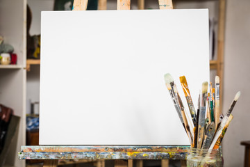 Art equipment: easel, brushes, tubes with paint, palette and paintings - Powered by Adobe