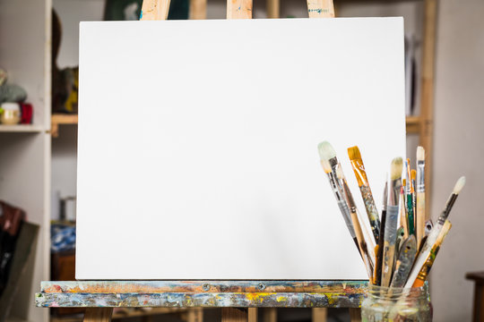 Art equipment: easel, brushes, tubes with paint, palette and paintings