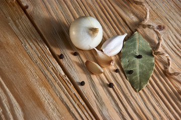 onion, garlic, black pepper and bay leaf on a wooden background