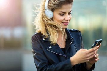 Woman listening to music with her smartphone outside
