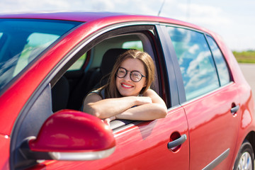 Young woman in car. Girl driving a car.  Smiling young woman sitting in red car

