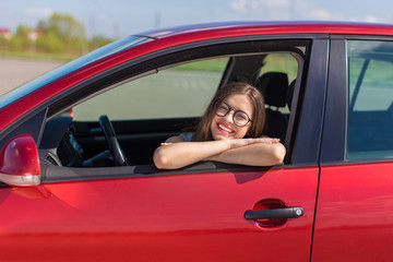 Young woman in car. Girl driving a car.  Smiling young woman sitting in red car
