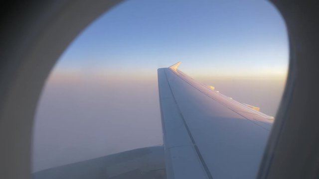 Morning flight. View to the airplane wing, sky and clouds through the illuminator