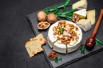Camembert cheese and walnuts on stone serving board