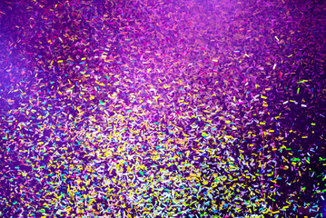 Thousands of confetti fired on air during a festival at night. Image ideal for backgrounds. Multicolor are the confetti in the picture. Purple/magenta is the tonality of the background