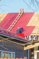 the employee covers the roof of a wooden house with tiles