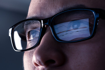the abstract image of the businessman wear a glasses looking at the stock trading chart on the computer screen. the concept of business, technology, trading, information and internet of things.