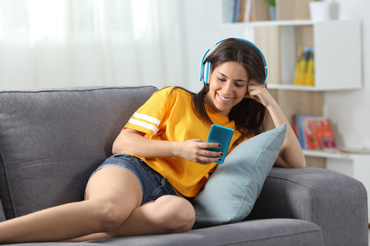 Happy modern teen listening to music on a couch