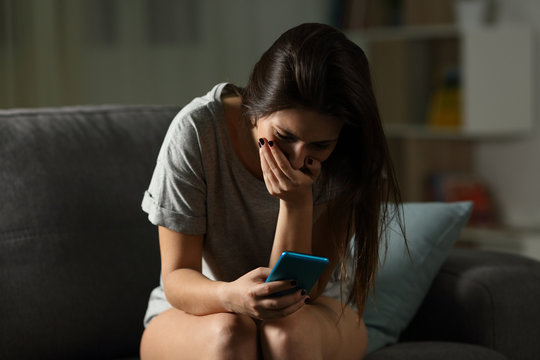 Sad teen receiving bad news online at home