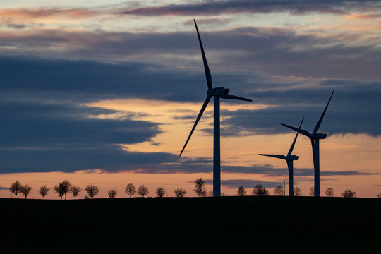 silhouette of three windmills at sunset