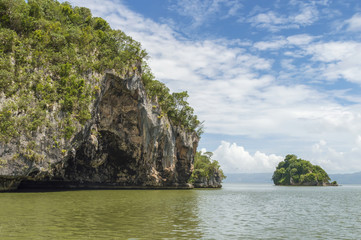 Obraz premium small islands, rocks in the Atlantic Ocean, covered with tropical vegetation, against the sky and clouds, Los Haitises National Park, of Samana Bay, Dominican Republic