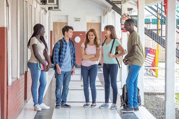 Group of mixed races teenagers talking standing in school hallway