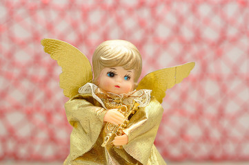 An angel used for decorating a christmas tree against a red background