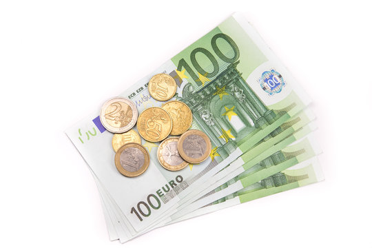 Stack of Euro banknotes and coins isolated. 100 Euro banknotes. European currency money banknotes isolated on white backdrop. Top view closeup. Salary, savings, european union economic crisis concept.