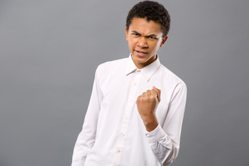 Aggressive look. Angry young man looking at you while showing you his fist