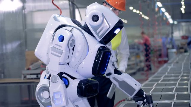 Factory worker checks droid's work, close up.