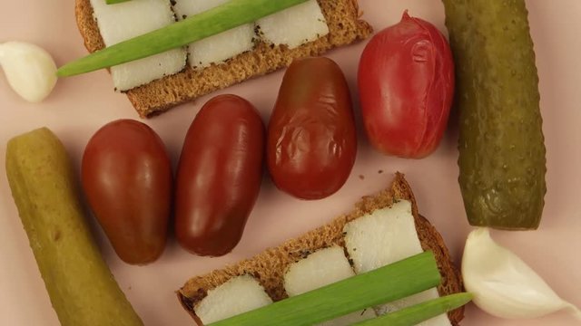 A plate with traditional Ukrainian snacks: black bread, green onions, lard, pickled tomatoes and cucumbers, garlic