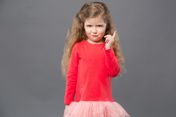 Emotional child. Cute pretty girl standing against grey background while talking to you