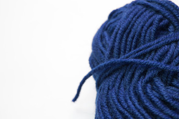 Fototapeta na wymiar Clew of deep blue knitting wool yarn aside on white surface, handicraft background