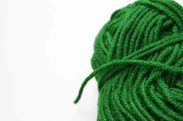 Clew of grassy green knitting wool yarn aside on white surface, handicraft background