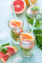 Refreshment grapefruit cocktail with mint on mint color background. Healthy citrus summer drink.