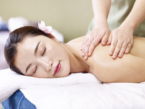 beautiful young asian woman receiving massage in spa salon