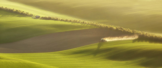Sunset light over plowing tractor in the spring, South Moravia, Czech Republic