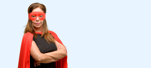 Middle age super hero woman wearing red mask and cape with crossed arms confident and happy with a big natural smile laughing isolated blue background © Krakenimages.com