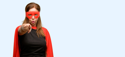 Middle age super hero woman wearing red mask and cape pointing to the front with finger isolated blue background