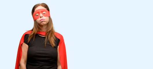 Middle age super hero woman wearing red mask and cape with sleepy expression, being overworked and tired isolated blue background