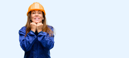 Engineer construction worker woman terrified and nervous expressing anxiety and panic gesture, overwhelmed isolated blue background