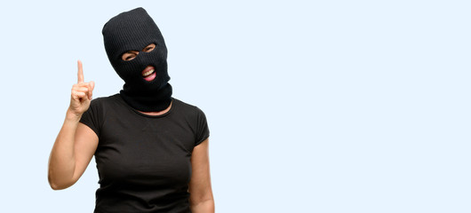 Burglar terrorist woman wearing balaclava ski mask pointing away side with finger isolated blue background