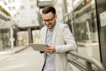 Young businessman with digital tablet by the office building