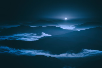 dark landscape with foggy mountains and full moon at night