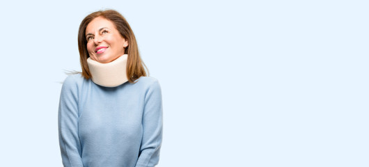 Injured woman wearing neck brace collar thinking and looking up expressing doubt and wonder isolated blue background