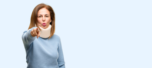 Injured woman wearing neck brace collar pointing to the front with finger isolated blue background