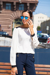 Young business woman with blue mirrored sunglasses calling by phone