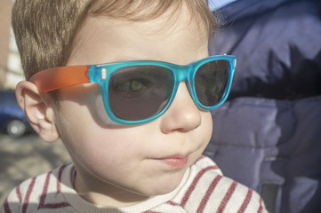 Blue eyes toddler boy protected with sunglasses. Children eye health concept