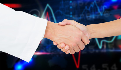 Extreme closeup of a doctor and patient shaking hands against stocks and shares on black background