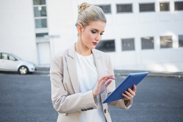 Serious stylish businesswoman scrolling on digital tablet