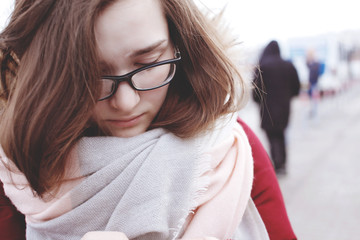 Cute young girl with glasses looks into smartphone