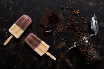 Double ice cream on a stick brown-beige. Ice cream coffee on a dark background, top view.Summer dessert