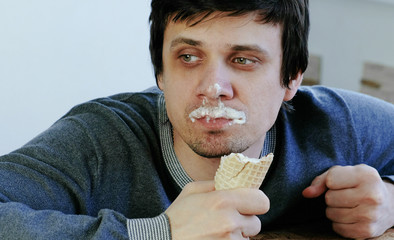 Closeup of young lousy man eats ice cream.