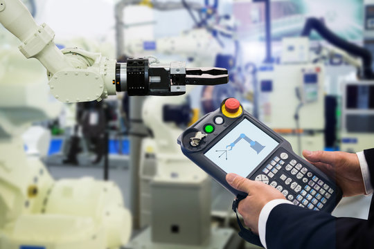 Engineer with teach pendant device. Programming robot with robotic arm. Smart factory 