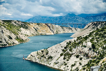 Rocky coast of the central part of Croatia. White clouds in the sky and blue sea.