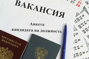 The employment record book, the passport and the questionnaire of the candidate for a position lie on a sheet of paper with the inscription Vacancy
