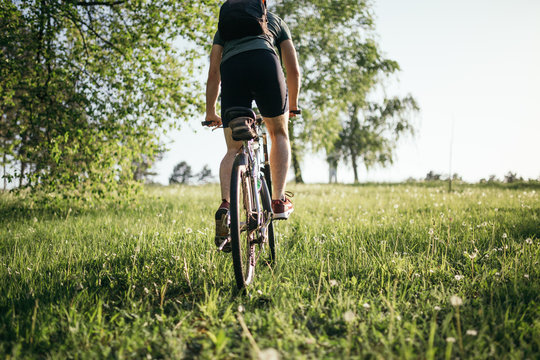 Cyclist man feet riding mountain bike on outdoor trail deep grass