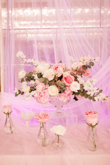 Beautiful decor with fabric and flowers. A large vase with white and pink flowers. Small vases with roses