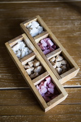 A wooden box with white brown lilac sugar stands on a wooden table. Pieces of colored sugar lilac  brown white in a wooden box