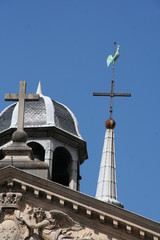 Roof of the catholic cathedral in Versailles, France, with cross, cock vane, bough-relief, blue sky